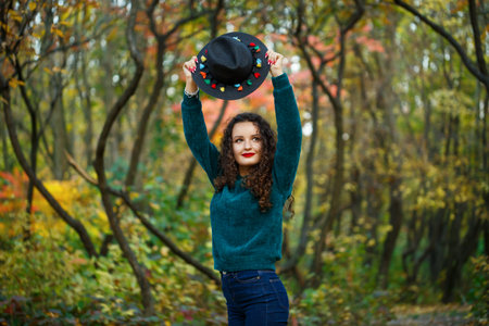 girl in the autumn forest with a hat in her handsの写真素材