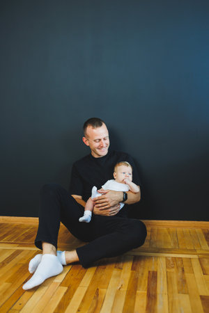 Smiling young dad holding his newborn son in his arms. Happy dad. Son and dad