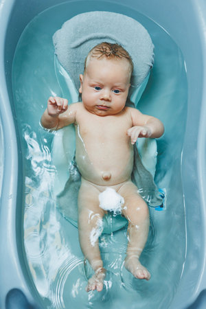 Bathing a baby in a bathtub, the baby is lying on a plastic stand. Baby care.の写真素材