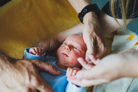 Newborn baby boy in the arms of his mother and father, lying on their arms close-up top view. Young parents hold their little baby. Healthy Lifestyle. Paternityの写真素材
