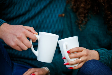 Couple in sweaters drinks tea in the autumn forestの写真素材