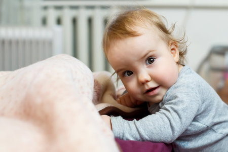 Photo portrait of a baby girl with pink cheeks. Baby gets to his feetの写真素材
