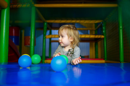 little girl 2 years old plays in a children's area with attractionsの写真素材