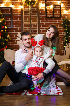 A happy family with a small child stands near a Christmas tree with toys and gifts. Happy childhood. New Year's festive atmosphere. Family relationship conceptの写真素材