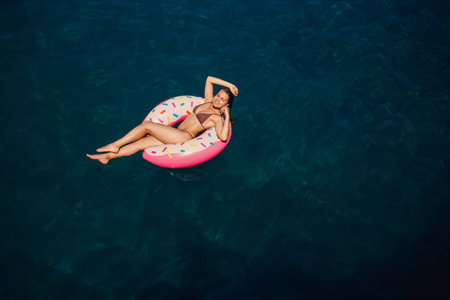 Young woman in a swimsuit swims on an inflatable ring in the sea. Summer vacation concept.の写真素材
