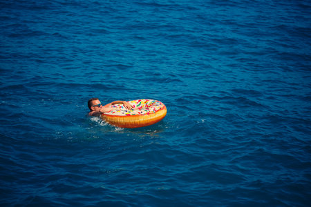 A man floats on an inflatable ring in the sea with blue water. Vacation at the sea on a sunny day. Turkey vacation conceptの写真素材