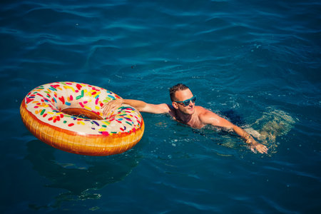 Young man on an inflatable ring in the sea resting and swimming on a sunny day