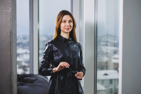 Portrait of a young slender woman in glasses and a black leather shirt. Modern woman on the...