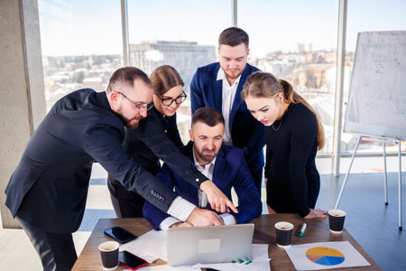 Happy business people looking at laptop presentation, success at work, sitting in modern office....