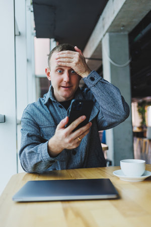 Excited young man in suit using mobile phone with funny expression, excited business man looking at his smartphone, reading good news via email, emotional lifestyle concept.の写真素材