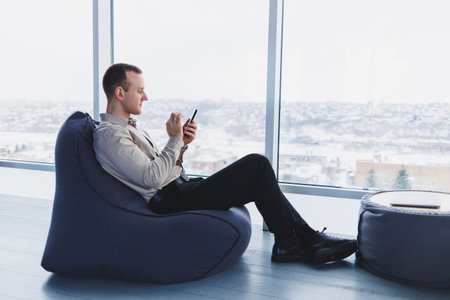 A businessman communicates with his clients by phone while sitting in a modern office workspace....