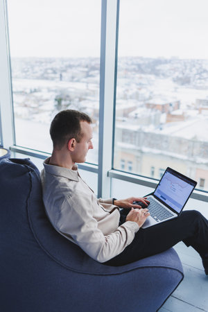 Concentrated young businessman looking at laptop screen, information online or working remotely...