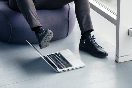Young successful male businessman is sitting near a large window in the office and relaxing. Rest after a working dayの写真素材