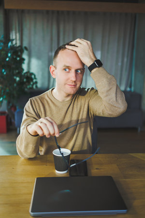 Top view of man in casual clothes with coffee sitting at workplace using netbook while working...
