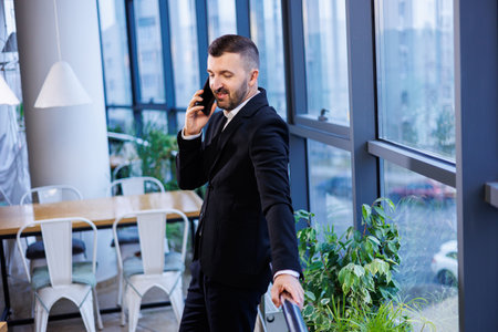 Handsome young businessman in modern suit using his mobile phone, successful man talking on the...