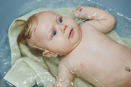 A small newborn boy of 5 months is bathing in a bathtub. Baby care.の写真素材