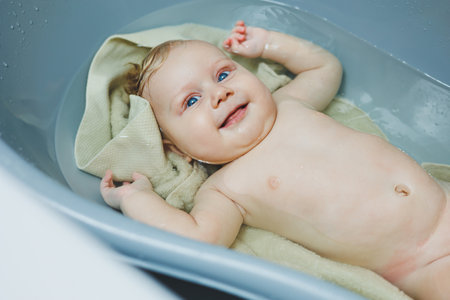 Photo of a 5-month-old baby lying in a baby bath. A four-month-old baby is bathing in water. Caring...