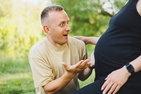 A man hugs the belly of his pregnant wife. Pregnancy. A happy couple is expecting a baby.の写真素材