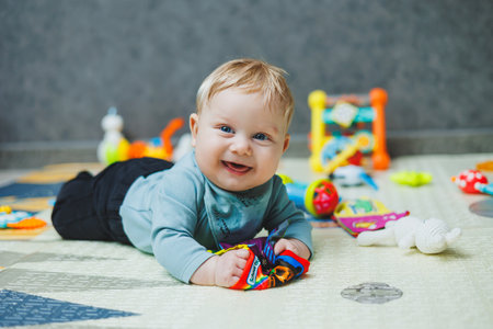 The baby lies on a thermal mat and plays. Self-development of a newborn child. Toys for child...