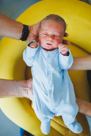 A newborn baby in the hands of his parents, clothes for a newborn baby. Cotton romper on a newborn boy.の写真素材