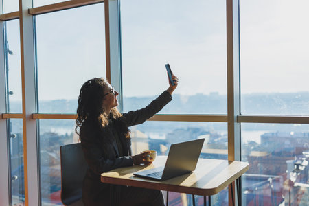 Young freelancer woman. Young woman working with laptop in coworking space and talking on phone,...