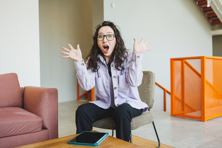 Curly female student working in bright cafe online looking at laptop. Remote work with a laptop in a cozy work cafeの写真素材