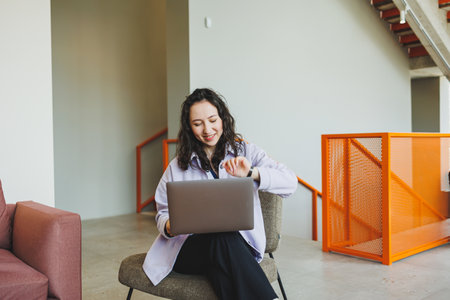 Curly female student working in bright cafe online looking at laptop. Remote work with a laptop in a...