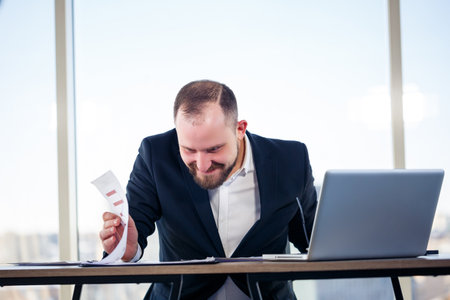 The corporate madman is sitting at the computer in the office and going crazy, the emotional portrait of the man at the table. Crazy worker at his workplaceの写真素材