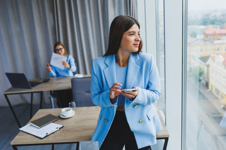 European businesswoman while working in the office. Young serious Millennial brunette woman in a jacket. The concept of freelance and remote work. Modern women's lifestyleの写真素材