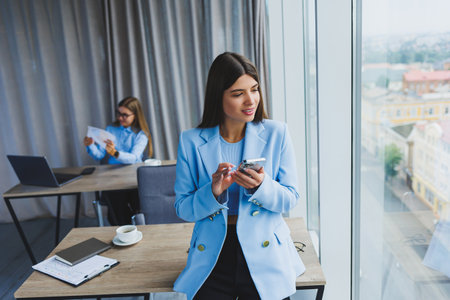 European businesswoman while working in the office. Young serious Millennial brunette woman in a jacket. The concept of freelance and remote work. Modern women's lifestyleの写真素材