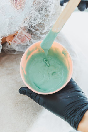 A woman is lying down at a dermatologist's appointment. Facial skin treatment. Mixing the face maskの写真素材