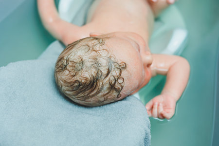 Bathing a baby in a bathtub on a stand. Baby's first bath at home after birth.の写真素材