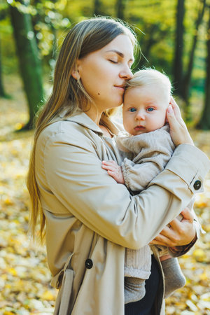 Happy young mother hug her little son in the sun on a warm spring or summer day in the park. The sun shines light in an apple orchard or in a park. Mother and son family concept in natureの写真素材