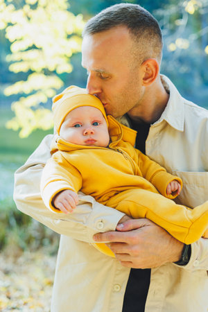 Young dad and little son in the park outdoors. Dad holds and kisses his son. Happy father and son.の写真素材