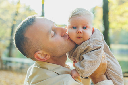 Happy young dad hug his little son in the sun on a warm spring or summer day in the park. Sunshine...