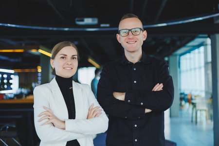 Two business people man and woman are standing in a modern office and posing for the camera.の写真素材