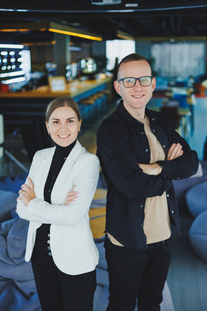 Two business people man and woman are standing in a modern office and posing for the camera.の写真素材
