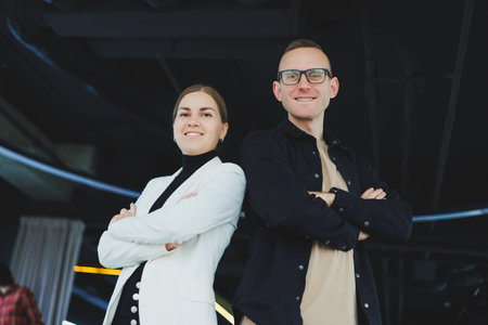 Two business people man and woman are standing in a modern office and posing for the camera.の写真素材