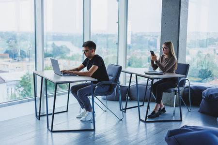 Young colleagues in the office at the desktop with a laptop. Young modern colleagues in smart casual...