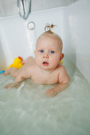 A baby 6-month-old child is taking a bath in the bathroom. Baby skin care. Child hygiene.