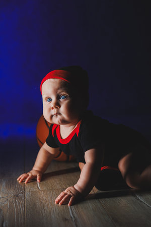 Baby 7 months with a basketball. Sports for kids. Cotton clothes for babies