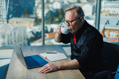 The man is a stylish freelancer, a gray-haired businessman on a workplace in the office. Adult...
