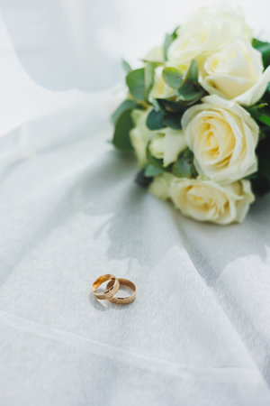 Precious gold rings for newlyweds on a background of flowers. Wedding rings for a couple.の写真素材