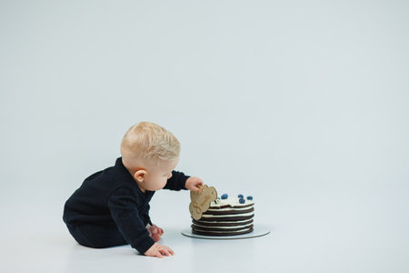a little boy of 8 months on a white background lies near a cake. sweet cake for a little boy.の写真素材