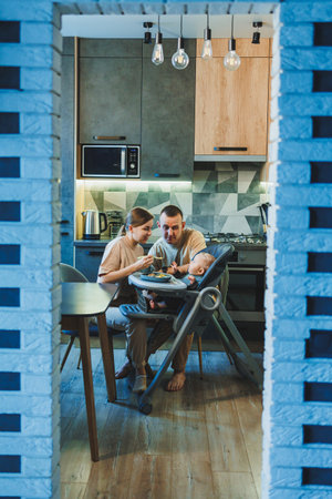The first pure baby food. Mother gives a spoonful of vegetables in a chair for feeding at home. Baby food at home. Children's dietの写真素材