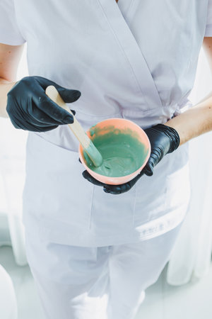 A woman is lying down at a dermatologist's appointment. Facial skin treatment. Mixing the face maskの写真素材