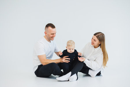 Young happy family couple with baby son on white background. Mom and dad with a baby on a white background.の写真素材