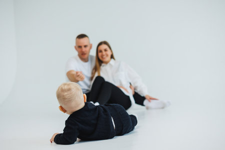 Young happy family couple with baby son on white background. Mom and dad with a baby on a white background.の写真素材