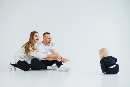 Young happy family couple with baby son on white background. Mom and dad with a baby on a white background.の写真素材