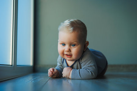 Portrait of a small baby boy in a cotton bodysuit with a smile on his face. The face of a blue-eyed baby with a smile.の写真素材